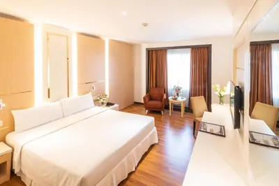 a hotel room with a large bed and a television at Zenith Sukhumvit Hotel, Bangkok in Bangkok