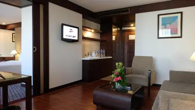 a hotel room with a bed and a living room at Zenith Sukhumvit Hotel, Bangkok in Bangkok