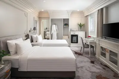 a hotel room with two beds and a television at Kingston Suites Bangkok in Bangkok