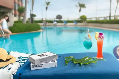 a table with a drink on it next to a pool at The Emerald Hotel in Bangkok