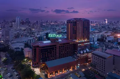 a city at night with a sign on top of a building at The Emerald Hotel in Bangkok