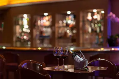 a table with two wine glasses and a basket of wine bottles at The Emerald Hotel in Bangkok