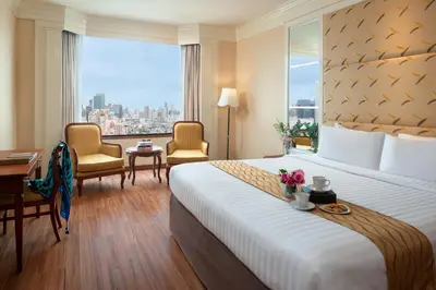a hotel room with a large bed and a large window at The Emerald Hotel in Bangkok