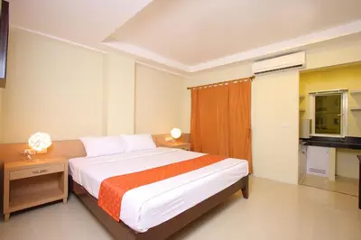 a bedroom with a large bed with an orange blanket at Sunday Platinum Suites in Bangkok