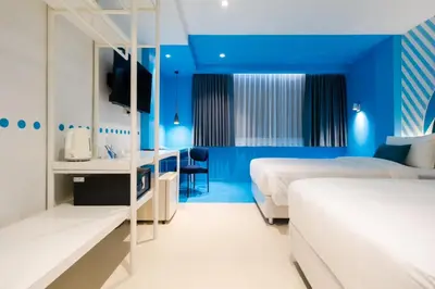 a hotel room with two beds with blue walls at Budacco The Living Place in Bangkok