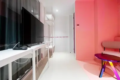 a living room with a television and a desk with a chair at Budacco The Living Place in Bangkok