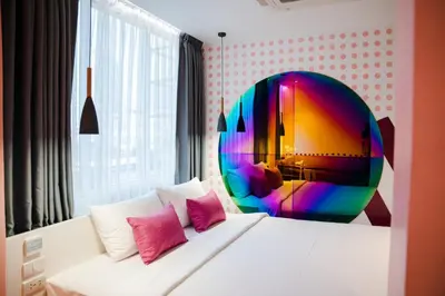 a bedroom with a white bed with a colorful mirror at Budacco The Living Place in Bangkok