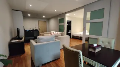 a living room with a couch and a table and a bedroom at The Bless Hotel and Residence in Bangkok