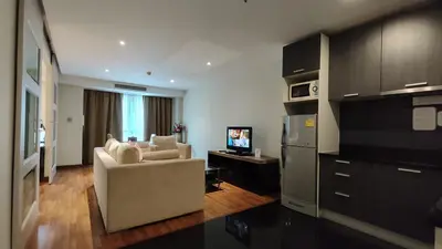 a living room with a couch and a television at The Bless Hotel and Residence in Bangkok
