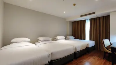 three beds in a hotel room with a window at The Bless Hotel and Residence in Bangkok