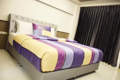 a bed with a purple and yellow blanket and a window at Family Suite Room Pratunam in Bangkok