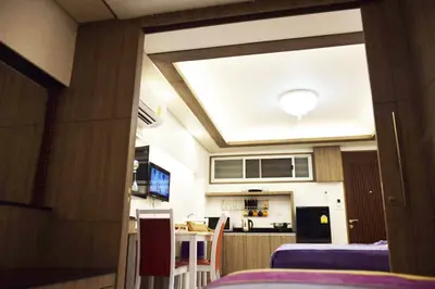 a room with a kitchen and a table with chairs at Family Suite Room Pratunam in Bangkok
