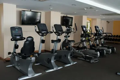 a gym with a bunch of exercise bikes and a flat screen tv at The Aiyapura Bangkok in Bangkok