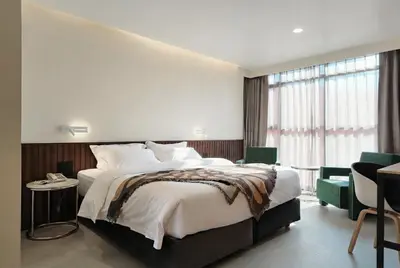 a bedroom with a large bed and a large window at Grand Inn Hotel in Bangkok