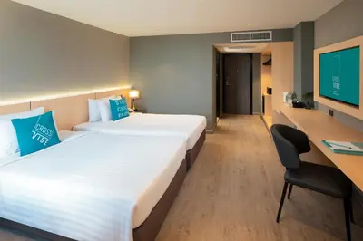 a hotel room with two beds and a desk and a tv at Cross Vibe Bangkok Srinakarin in Bangkok
