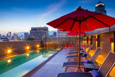 a pool with chairs and an umbrella on a building at Hotel Solo, Sukhumvit 2, Bangkok - SHA Extra Plus in Bangkok