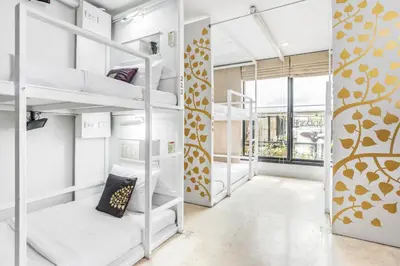 a room with white bunk beds with a window at Nappark Hostel @Khao San in Bangkok