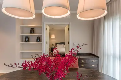 a dining room with a table with red flowers on it at At 21 Saladaeng in Bangkok
