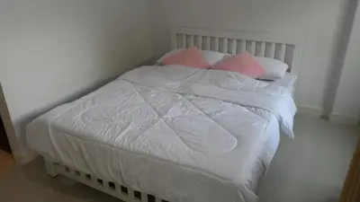 a bed with white sheets and pink pillows at Little Home in Nonthaburi