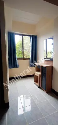 a room with a bed and a desk and windows at Nontharat Mansion in Nonthaburi