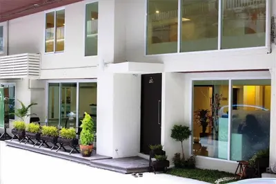 a white building with plants in front of it at Nantra de Comfort in Bangkok