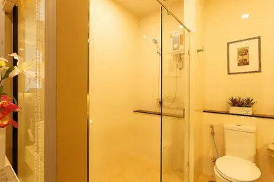 a bathroom with a toilet and a glass shower at Green Point Residence Hotel in Bangkok