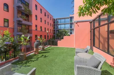 a small courtyard in a building with grass and chairs at Baansuanprannok Hotel in Bangkok
