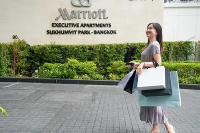 a woman holding shopping bags in front of a building at Marriott Executive Apartments Sukhumvit Park, Bangkok in Bangkok