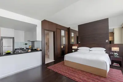 a bedroom with a large white bed and a kitchen at Marriott Executive Apartments Sukhumvit Park, Bangkok in Bangkok