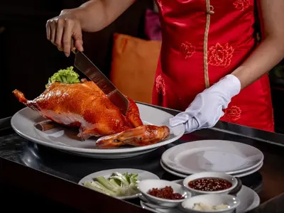 a person cutting a turkey on a plate with a knife at Renaissance Bangkok Ratchaprasong Hotel by Marriott in Bangkok
