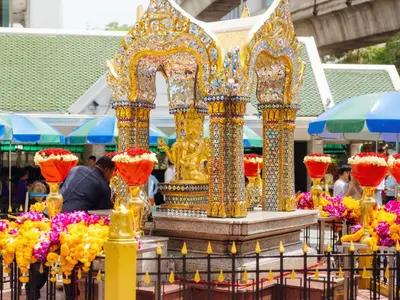 a man standing in front of a shrine with flowers at Renaissance Bangkok Ratchaprasong Hotel by Marriott in Bangkok