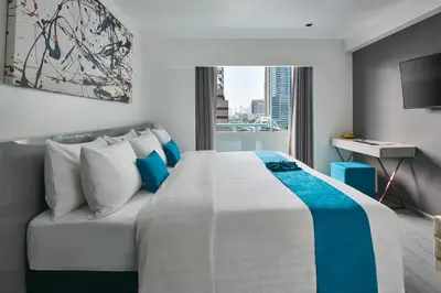 a hotel room with a large bed and a window at Sora Hotel Silom in Bangkok