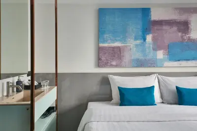 a bedroom with a bed with blue pillows and a painting at Sora Hotel Silom in Bangkok