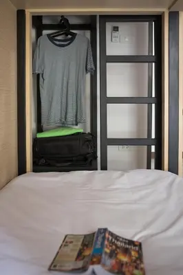 a bedroom with a bed and a closet with a shirt at Le Bonheur Poshtel in Bangkok