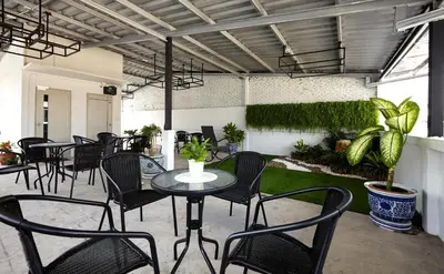 a patio with black chairs and tables and plants at Le Bonheur Poshtel in Bangkok