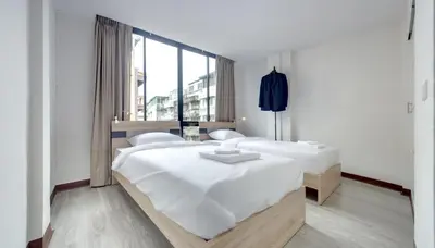 a bedroom with two beds and a large window at Le Bonheur Poshtel in Bangkok