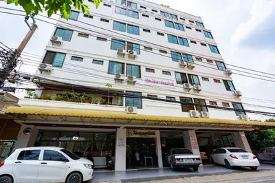 a white building with cars parked in front of it at Tat Hotel in Bangkok