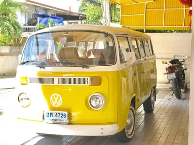 a yellow and white van parked next to a motorcycle at Tat Hotel in Bangkok