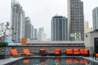 a rooftop pool with orange chairs and a city skyline at Ramada Sukhumvit Soi Eleven in Bangkok