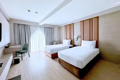 a hotel room with two beds and a television at Ramada Sukhumvit Soi Eleven in Bangkok