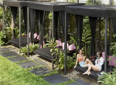 two women sitting on a gazebo in a garden at Sora Resort & Suites Sukhumvit in Bangkok