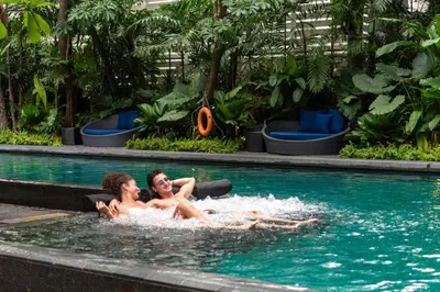 two people laying in the water in a swimming pool at Sora Resort & Suites Sukhumvit in Bangkok