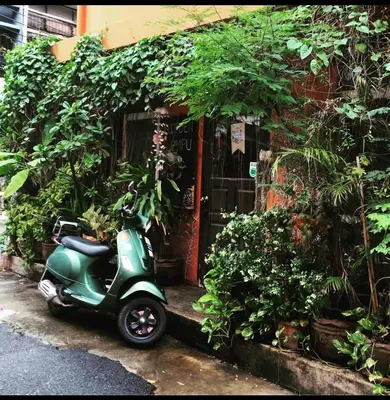 a green scooter parked in front of a building at Hidden Lumpu in Bangkok