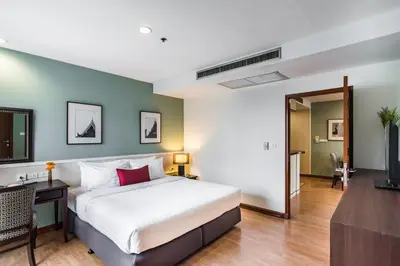 a bedroom with a bed and a desk and a television at Evergreen Place Siam by UHG in Bangkok