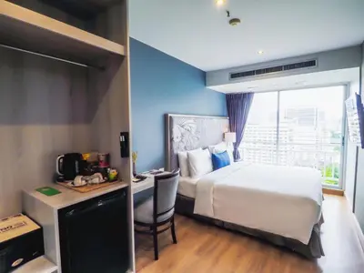 a hotel room with a bed and a desk with a microwave at Evergreen Place Siam by UHG in Bangkok