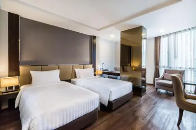 a hotel room with two beds and a chair at SureStay Plus by Best Western Sukhumvit 2 in Bangkok