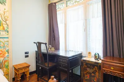 a desk with a chair in a room with a window at The Unforgotten B&B in Bangkok