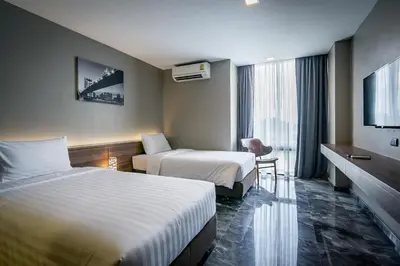 a hotel room with two beds and a television at Onix Hotel Bangkok in Bangkok