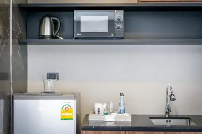 a small kitchen with a microwave and a refrigerator at Onix Hotel Bangkok in Bangkok