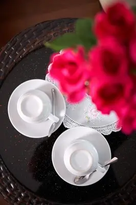 two cups and saucers on a table with a flower at KC Place Hotel Pratunam in Bangkok
